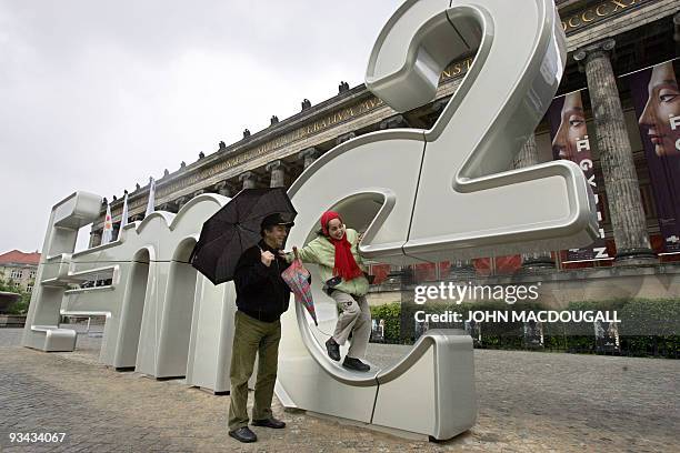 Tourists climb on a giant sculpture featuring Albert Einstein's formula "E=mc2" in front of Berlin's Altes Museum 19 May 2006. The sculpture, the...