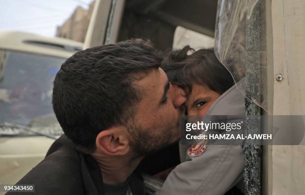 Man kisses a child as people board Syrian Red Crescent buses evacuating humanitarian cases from Douma, Eastern Ghouta, on the eastern outskirts of...