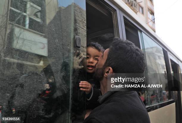 Man kisses a child as people board Syrian Red Crescent buses evacuating humanitarian cases from Douma, Eastern Ghouta, on the eastern outskirts of...
