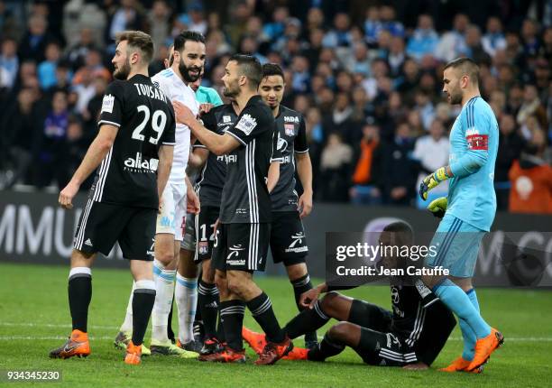 Adil Rami of OM is restrained by Jeremy Morel of Lyon while Marcelo Guedes of Lyon sits on the pitch and goalkeeper of Lyon Anthony Lopes looks on...