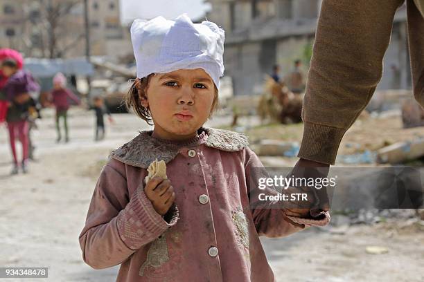 Wounded Syrian girl walks with her parents in the town of Kfar Batna, Southeastern Ghouta, on the eastern outskirts of the capital Damascus, on March...
