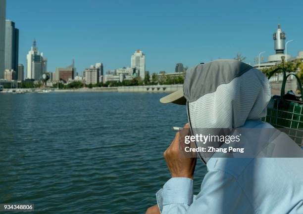 Man smokes beside Haihe river, which flows through the city center. . In 2017, Tianjin's gross domestic product was 1859.5 billion yuan, an increase...