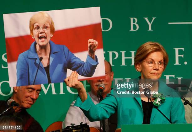Senator Elizabeth Warren holds up a picture of herself with President Donald Trump's hair during the annual St. Patrick's Day Breakfast at the...