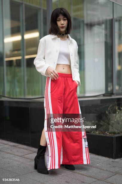Guest is seen wearing a white jacket and crop top with red Adidas track pants, black shoes and black leather choker during the Amazon Fashion Week...