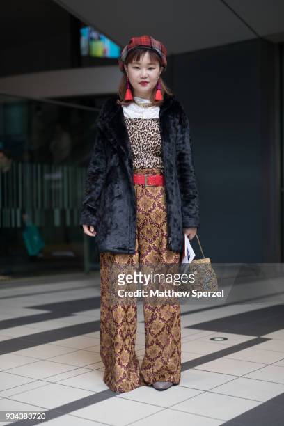 Guest is seen wearing an animal print top, black fur coat, gold/burgundy design pants, red belt and plaid beret during the Amazon Fashion Week TOKYO...