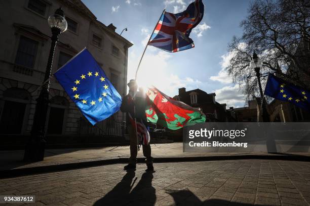 Brexit protesters wave flags made up of a European Union flags, left and right, British Union flags, also known as a Union Jack, center top, and a...