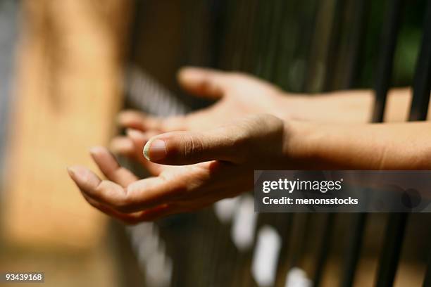 hands held out from behind bars - nail bar stock pictures, royalty-free photos & images