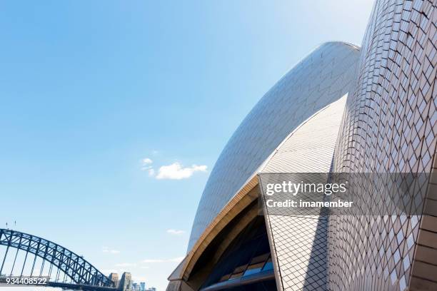 closeup sydney opera house roofline with view of harbour bridge - sydney harbour bridge opera house stock pictures, royalty-free photos & images