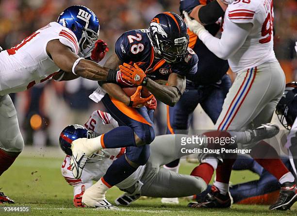 Running back Correll Buckhalter of the Denver Broncos rushes as Justin Tuck of the New York Giants gets a hand on the ball as he attempts to make the...