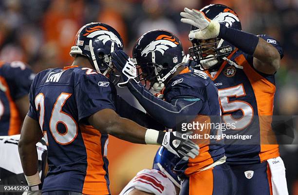 Andre Goodman of the Denver Broncos is congratulated by Ty Law and DJ Williams after his fourth quarter interception of quarterback Eli Manning of...