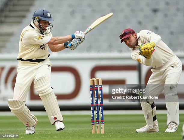 David Hussey of Victoria plays a shot past Queensland wicketkeeper Chris Hartley during day one of the Sheffield Shield match between the Victorian...