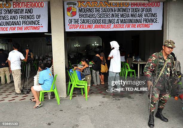 Soldier stands at the entrance of a funeral parlor where the bodies of journalists killed in an election-related massacre in the southern Philippine...