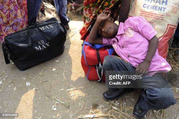 Bangladeshi boy rests as he and his family wait at a bus station in Dhaka on November 27, 2009 as thousands of Muslims rush home to their families in...