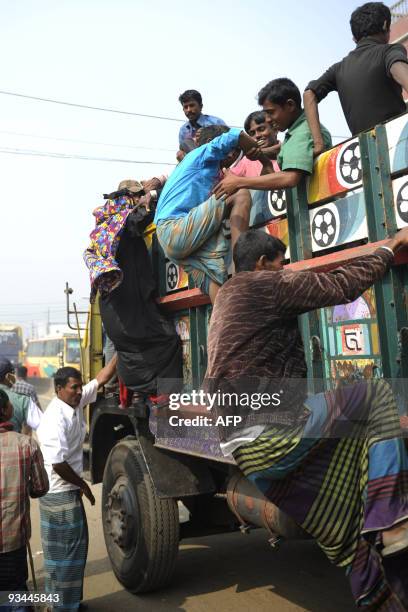 Bangladeshis climb into a truck at a bus station in Dhaka on November 27, 2009 as thousands of Muslims rush home to their families in remote villages...