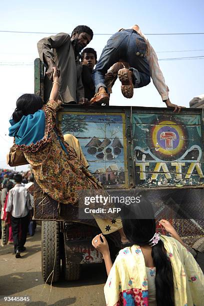 Bangladeshis climb into a truck at a bus station in Dhaka on November 27, 2009 as thousands of Muslims rush home to their families in remote villages...