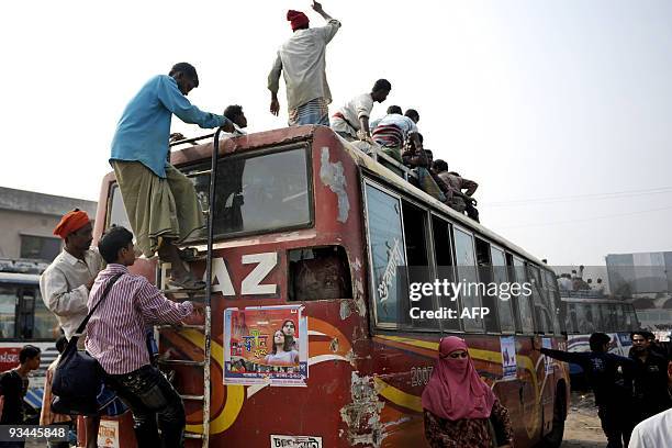Bangladeshis climb onto a bus at a bus station in Dhaka on November 27, 2009 as thousands of Muslims rush home to their families in remote villages...