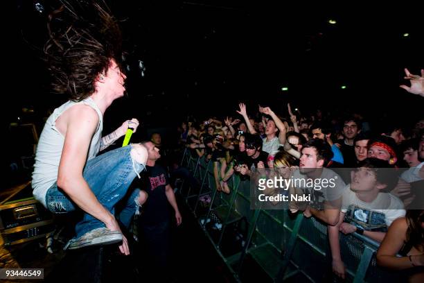 Spencer Chamberlain of Underoath performs kneeling on the front of the stage, singing at cheering fans in the front row of the audience at Estragon...