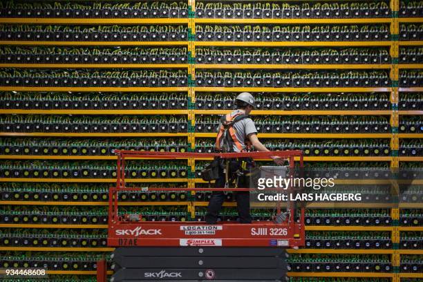 Technician inspects the backside of bitcoin mining at Bitfarms in Saint Hyacinthe, Quebec on March 19, 2018. - Bitcoin is a cryptocurrency and...
