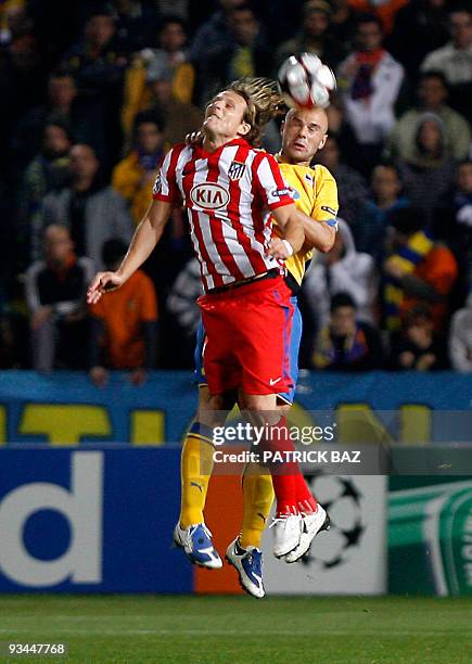 Apoel Nicosia's Nectarios Alexandrou jumps for the ball with Atletico Madrid's Diego Forlan during their UEFA Champions League group D football match...