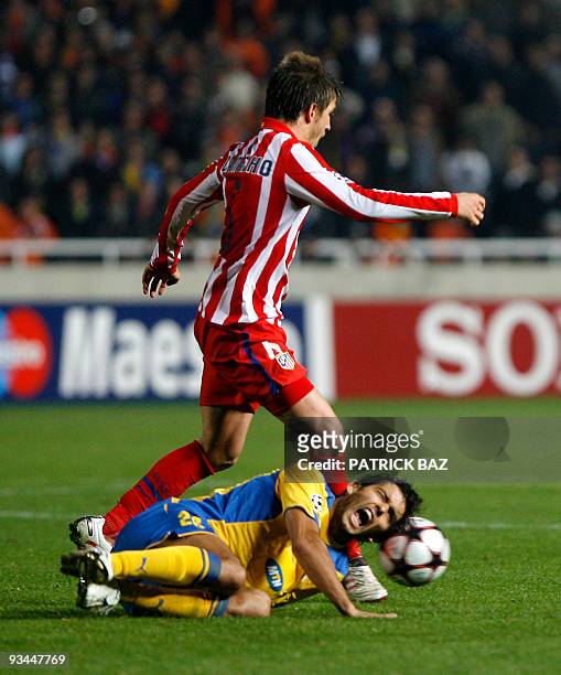 Apoel Nicosia's Nuno Morais falls to the ground as he vies with Atletico Madrid's Ignacio Camacho during their UEFA Champions League group D football...