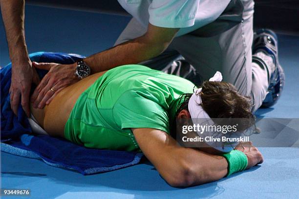 Rafael Nadal of Spain receives assistance as he lies on the court during the men's singles round robin match against Novak Djokovic of Serbia during...