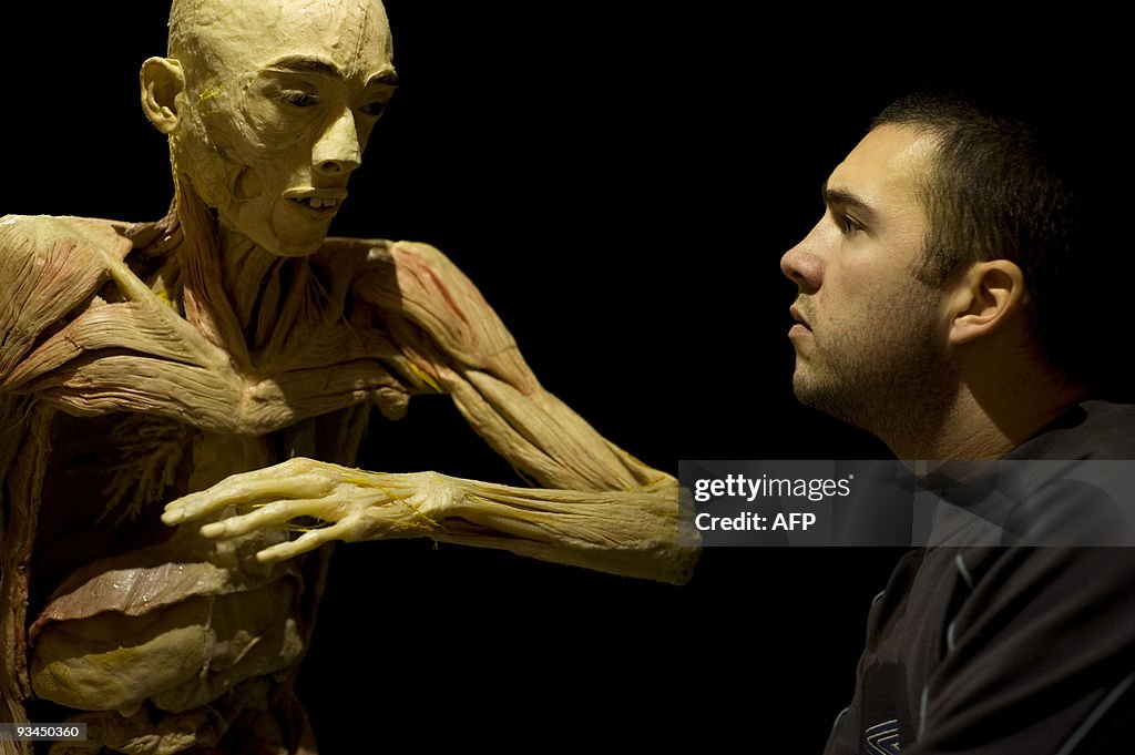 A visitor looks at a body on display at
