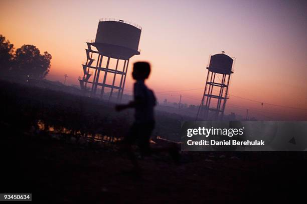 Children plays near water towers in front of their homes near the Union Carbide factory on November 27, 2009 in Bhopal, India. Twenty-five years...