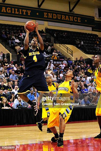 Darius Morris of the Michigan Wolverines attempts a shot against Maurice Acker of the Marquette Golden Eagles during the Old Spice Classic at...