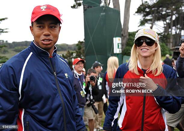 Team member Tiger Woods and his wife Elin Nordegren wait for the rest of the team to finish play after Woods sunk his putt on the 13th green to win...