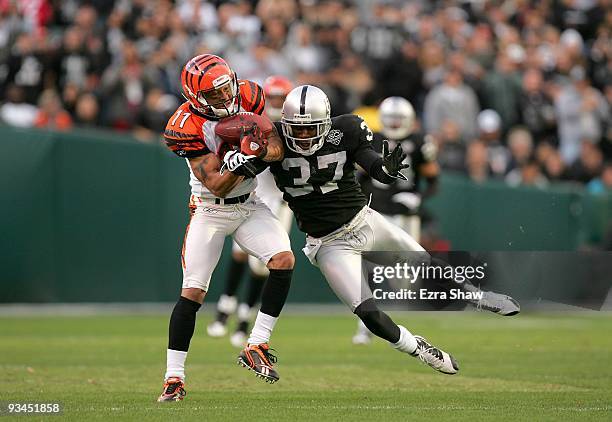 Laveranues Coles of the Cincinnati Bengals comes down with the ball while defended by Chris Johnson of the Oakland Raiders at Oakland-Alameda County...