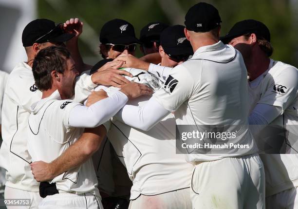 Daniel Vettori of New Zealand is embraced by his team as he celebrates the wicket of Mohammad Aamer of Pakistan to win the First Test match on day...