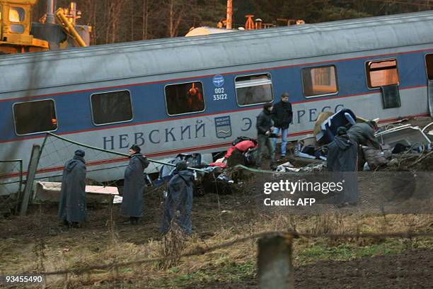 Experts inspect the debris of a damaged railway carriage near the village of Uglovka in Russia's Novgorod region on November 28 after a train...