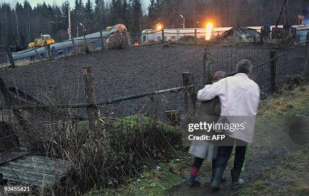 Local villagers pass by a damaged railway carriages near the village of Uglovka in Russia's Novgorod region on November 28 after a train derailed...