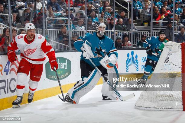 Martin Jones of the San Jose Sharks clears the puck against Luke Glendening of the Detroit Red Wings at SAP Center on March 12, 2018 in San Jose,...