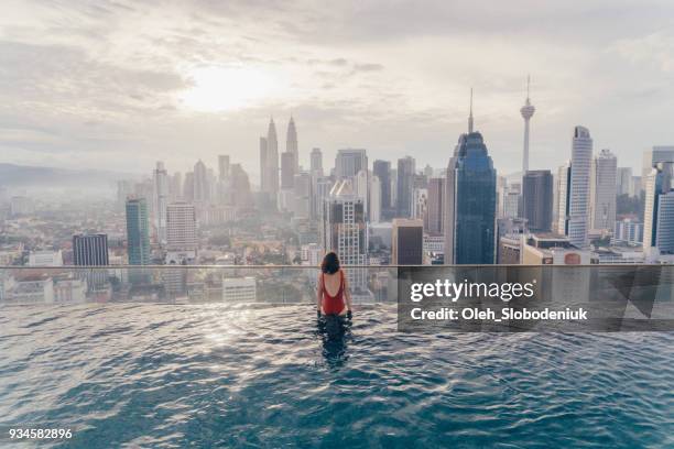 woman in the swimming pool with view of kuala lumpur - red swimwear stock pictures, royalty-free photos & images
