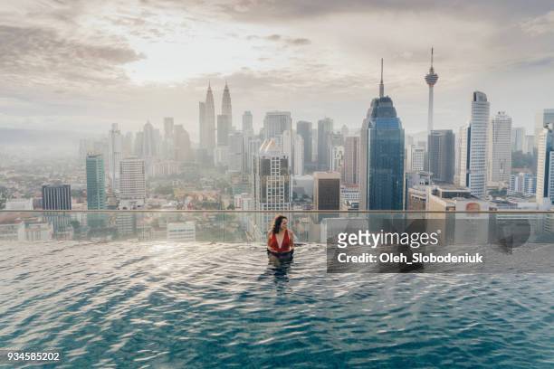 woman in the swimming pool with view of kuala lumpur - kuala lumpur stock pictures, royalty-free photos & images