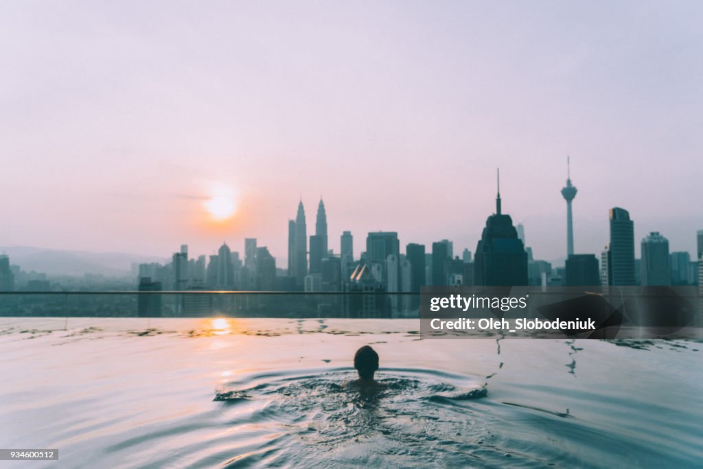 Woman in the swimming pool with view of Kuala Lumpur