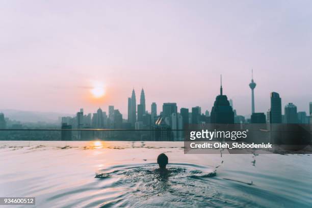 woman in the swimming pool with view of kuala lumpur - kuala lumpur stock pictures, royalty-free photos & images