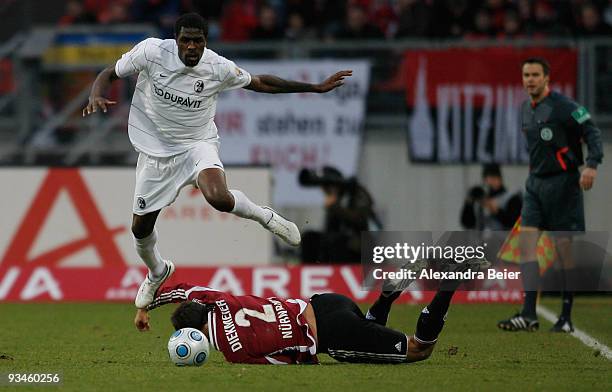 Dennis Diekmeier of Nuernberg falls as Mohamadou Idrissou of Freiburg runs for the ball during the Bundesliga match between 1. FC Nuernberg and SC...