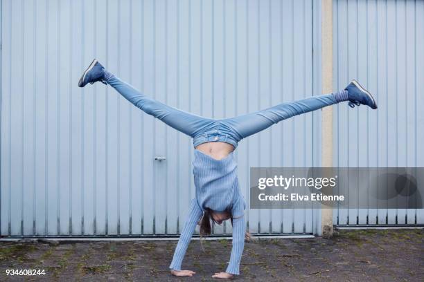 girl (10-11) wearing blue clothes and doing a cartwheel in front of blue garage doors - blue shoe foto e immagini stock