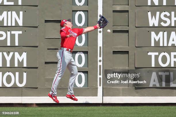 Rhys Hoskins of the Philadelphia Phillies is unable to catch the ball off the bat of Mookie Betts of the Boston Red Sox during a spring training game...