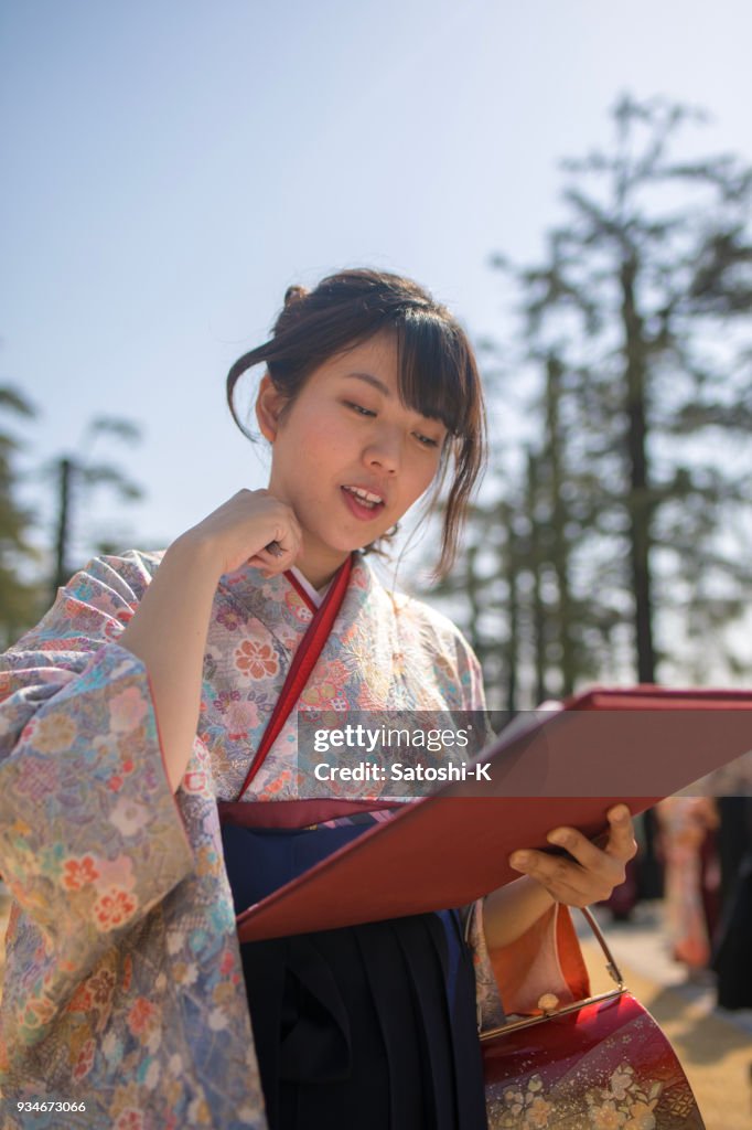 Joven leyendo el diploma en el día de la graduación