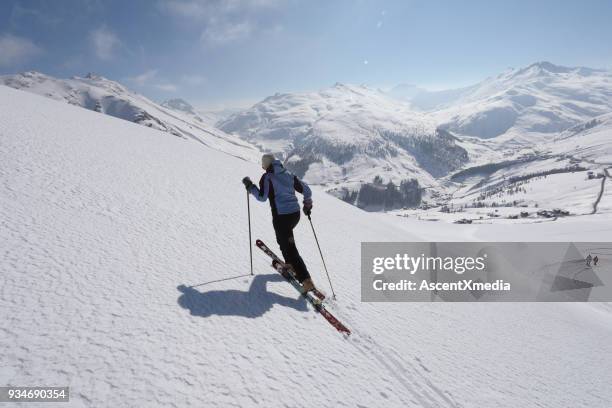 vrouwelijke ski bergbeklimmer bestijgt berghelling. - ski pants stockfoto's en -beelden