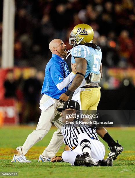 Jesse Ward of the UCLA Bruins is restrained by a team coach as a game offcial falls to the ground during a confrontation with USC Trojans players...