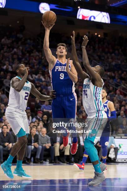 Dario Saric of the Philadelphia 76ers shoots the ball against Marvin Williams and Michael Kidd-Gilchrist of the Charlotte Hornets in the first...