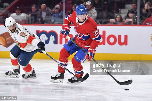 Mike Reilly of the Montreal Canadiens skates with the puck under pressure from Vincent Trocheck of the Florida Panthers in the NHL game at the Bell...