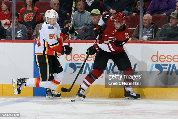 Brett Kulak of the Calgary Flames and Brendan Perlini of the Arizona Coyotes battle for the puck along the boards during the first period at Gila...