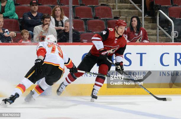Richard Panik of the Arizona Coyotes looks to pass the puck as Micheal Ferland of the Calgary Flames defends during the first period at Gila River...