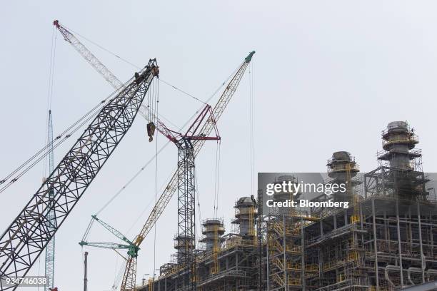 Cranes operate at a steam cracker unit at the under construction Petronas Nasional Berhad Refinery and Petrochemical Integrated Development Project,...