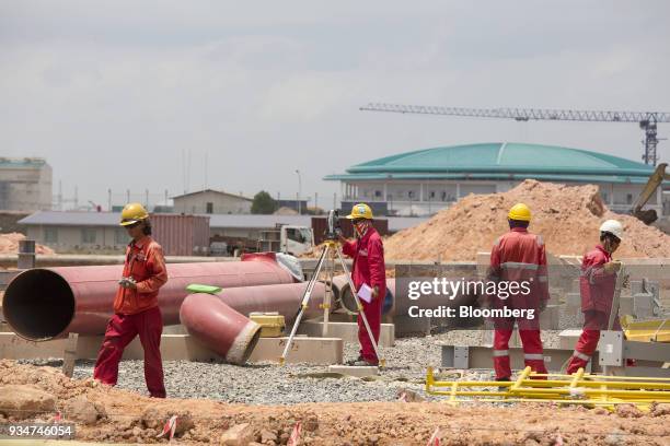 Surveyor, center, works at the under construction Petronas Nasional Berhad Refinery and Petrochemical Integrated Development Project, part of the...